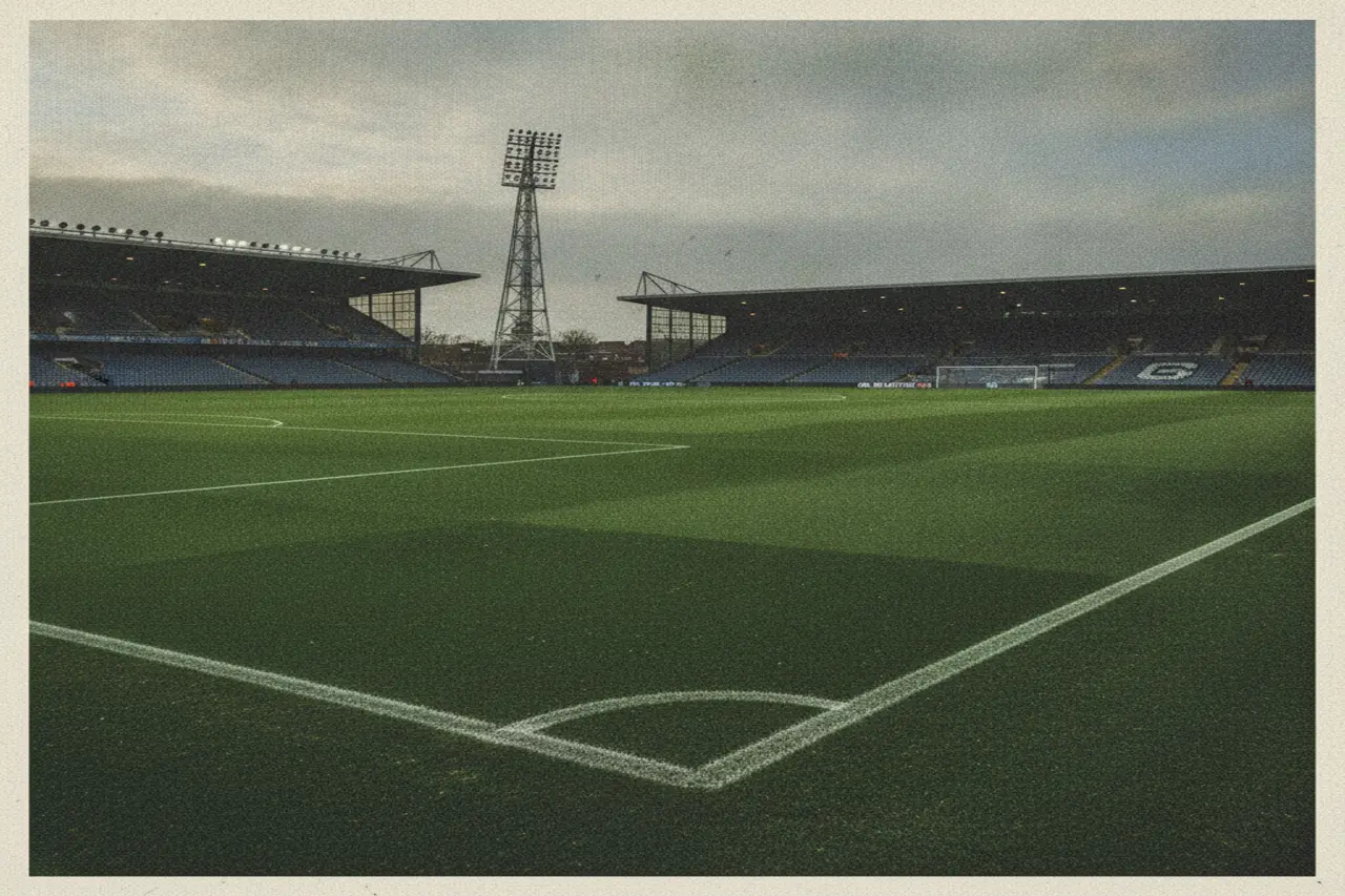 Atmospheric British football stadium pitch with freshly painted touchlines under soft afternoon skies